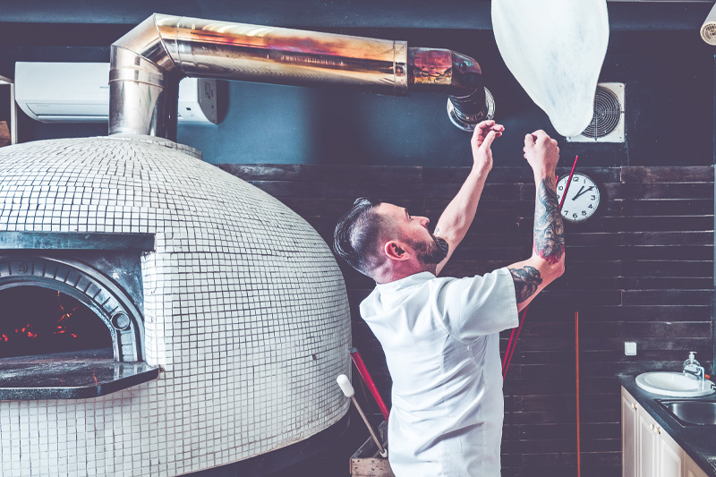 man tossing pizza in restaurant