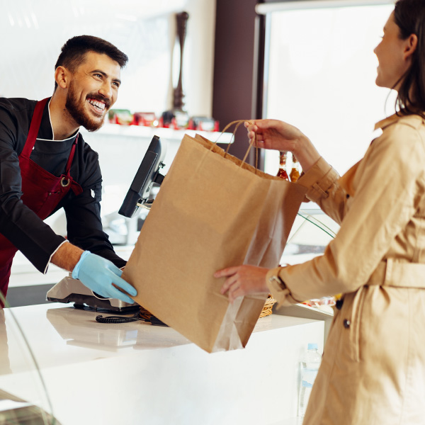 happy restaurant worker handing bag to customer